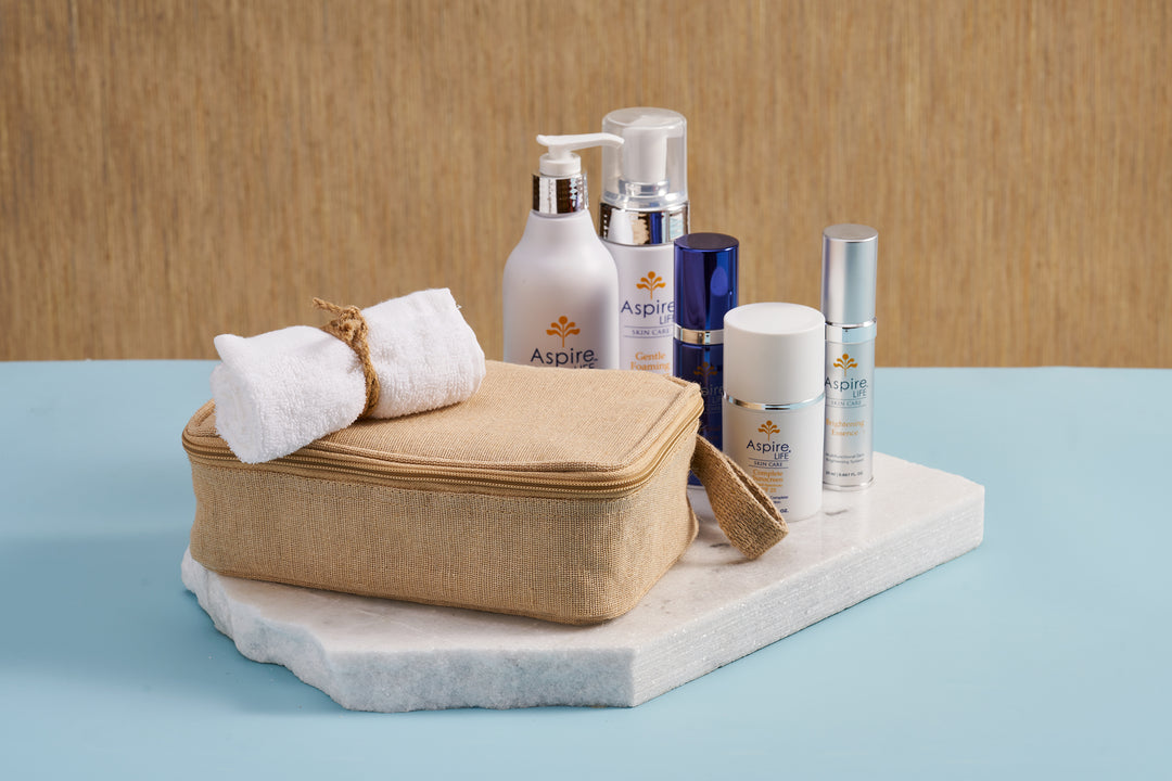 AspireLIFE® full skincare collection with five products displayed alongside a free organic bamboo washcloth and sustainable jute-blend travel kit.